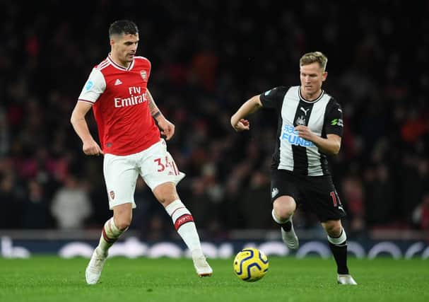 Granit Xhaka of Arsenal passes the ball under pressure from Matt Ritchie of Newcastle.