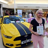 Richie Smith alongside his Mustang sports car and holding his book "The Art of Weeing In The Sink".