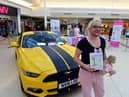 Richie Smith alongside his Mustang sports car and holding his book "The Art of Weeing In The Sink".