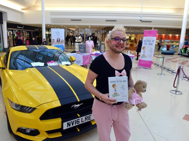 Richie Smith alongside his Mustang sports car and holding his book "The Art of Weeing In The Sink".