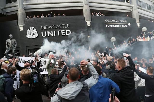 Newcastle United supporters celebrate outside the club's stadium following the announcement of a takeover a year ago.