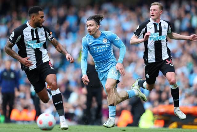 Jack Grealish of Manchester City is challenged by Jamaal Lascelles and Sean Longstaff of Newcastle United during the Premier League match between Manchester City and Newcastle United at Etihad Stadium on May 08, 2022 in Manchester, England. (Photo by Alex Livesey/Getty Images)