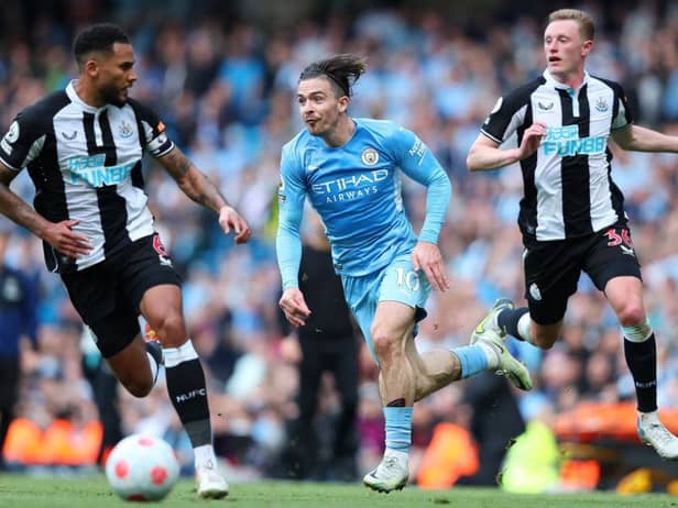 Jack Grealish of Manchester City is challenged by Jamaal Lascelles and Sean Longstaff of Newcastle United during the Premier League match between Manchester City and Newcastle United at Etihad Stadium on May 08, 2022 in Manchester, England. (Photo by Alex Livesey/Getty Images)