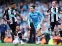 Jack Grealish of Manchester City is challenged by Jamaal Lascelles and Sean Longstaff of Newcastle United during the Premier League match between Manchester City and Newcastle United at Etihad Stadium on May 08, 2022 in Manchester, England. (Photo by Alex Livesey/Getty Images)
