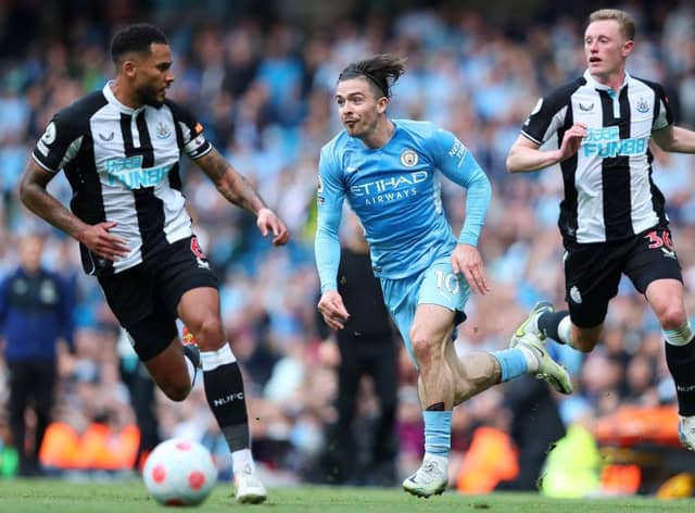 Jack Grealish of Manchester City is challenged by Jamaal Lascelles and Sean Longstaff of Newcastle United during the Premier League match between Manchester City and Newcastle United at Etihad Stadium on May 08, 2022 in Manchester, England. (Photo by Alex Livesey/Getty Images)