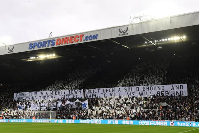 NEWCASTLE UPON TYNE, ENGLAND - OCTOBER 17: Fans of Newcastle show their support in front of the flags in the Gallowgate end of which reads the lyrics from the song 'Big River'  'Cause this is a mighty town, built upon solid ground, and everything they've tried so hard to kill, we will rebuild!' during the Premier League match between Newcastle United and Tottenham Hotspur at St. James Park on October 17, 2021 in Newcastle upon Tyne, England. (Photo by Stu Forster/Getty Images)