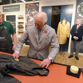 King Charles III, then the Prince of Wales, turns his hand to re-waxing a Barbour jacket.