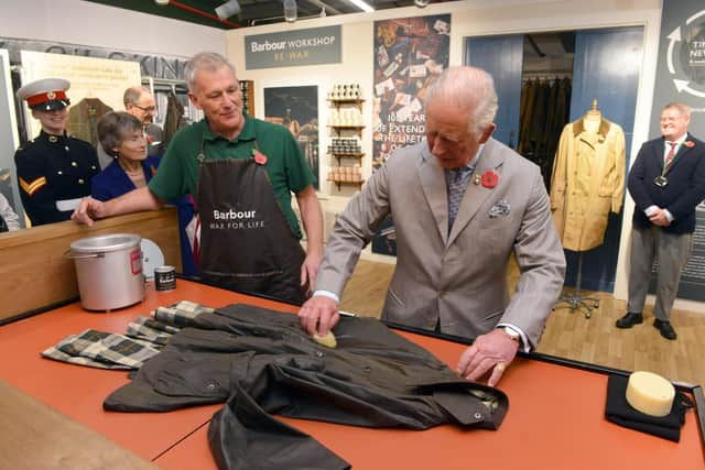 King Charles III, then the Prince of Wales, turns his hand to re-waxing a Barbour jacket.