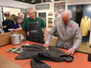 King Charles III, then the Prince of Wales, turns his hand to re-waxing a Barbour jacket.