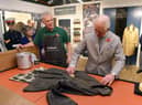 King Charles III, then the Prince of Wales, turns his hand to re-waxing a Barbour jacket.