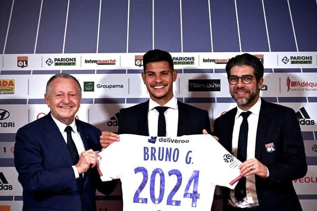 Lyon's Brazilian midfielder Bruno Guimaraes (C) holds the team's jersey flanked by Olympique Lyonnais president Jean Michel Aulas (L) and and former Olympique Lyonnais midfielder and sports director Juninho, at the Groupama stadium in Decines-Charpieu, near Lyon, central eastern France, on February 13, 2020.(Photo by JEFF PACHOUD/AFP via Getty Images)