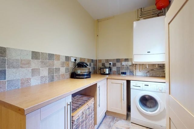 Storage cupboards are set beneath a timber-effect worksurface with a tiled splashback. There is connection for a washing machine and space for other white goods. The gas boiler is situated in the utility room.