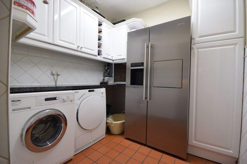 Laminate worktops, space for a washing machine, space for a dryer, a range of wall-mounted storage cupboards.