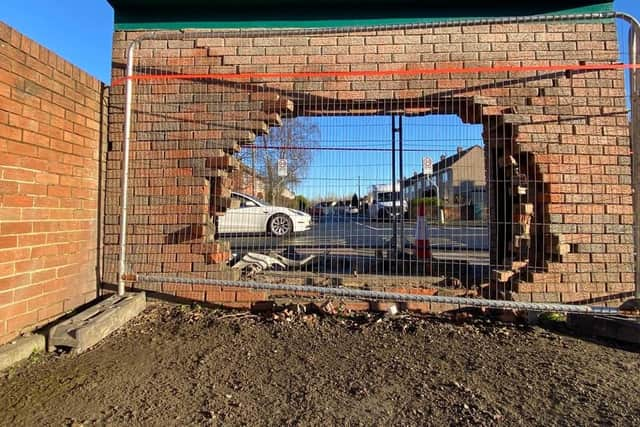 The hole in the back wall of the brick bus stop which the vehicle went through.