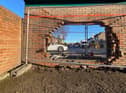The hole in the back wall of the brick bus stop which the vehicle went through.