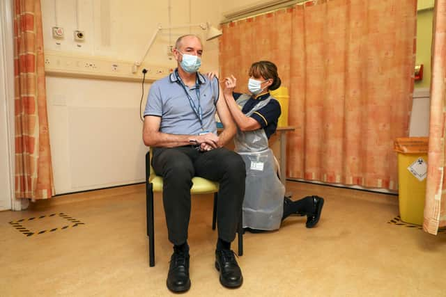 Professor Andrew Pollard, Director of the Oxford Vaccine Group, and a professor of paediatric infection and immunity receives the Oxford University/AstraZeneca COVID-19 vaccine from nurse Sam Foster