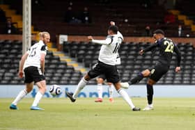 Joe Willock of Newcastle United scores their sides first goal whilst under pressure from Tosin Adarabioyo of Fulham during the Premier League match between Fulham and Newcastle United at Craven Cottage on May 23, 2021 in London, England.