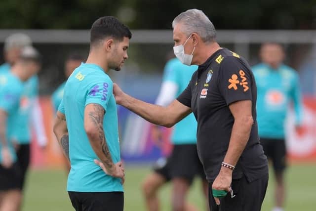 Brazil's coach Tite (R) talks to player Bruno Guimaraes  (Photo by DOUGLAS MAGNO/AFP via Getty Images)