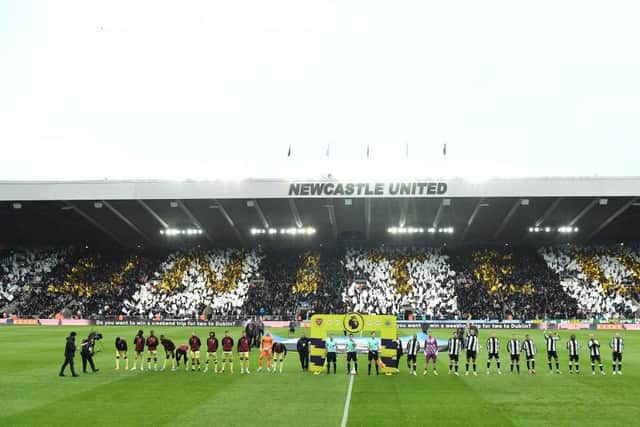 The players line up as a flag display in the East Stand shows the word 'United'  before the Premier League match between Newcastle United and Arsenal at St. James Park on May 16, 2022 in Newcastle upon Tyne, England. (Photo by Stu Forster/Getty Images)