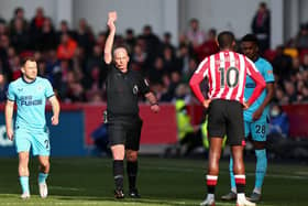 Referee Mike Dean shows a red card to Josh Dasilva of Brentford after a foul during the Premier League match between Brentford and Newcastle United at Brentford Community Stadium on February 26, 2022 in Brentford, England. (Photo by Marc Atkins/Getty Images)