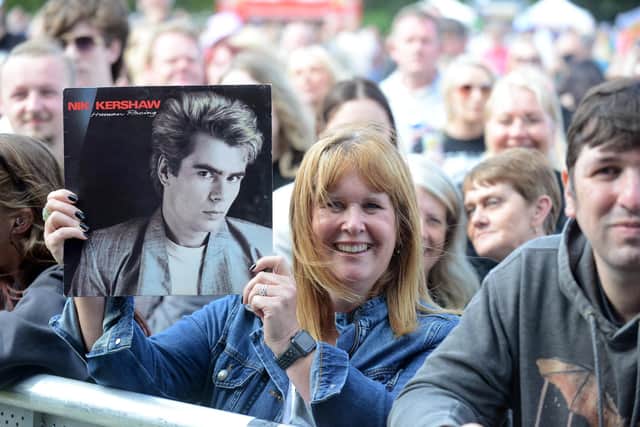 A fan holds up one of Nik Kershaw's old albums as he performs on stage.