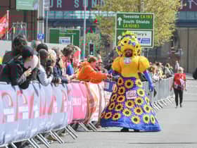 Colin Burgin-Plews dressed in a giant sunflower dress as he approaches the finish line.