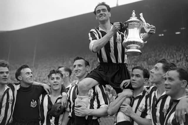 Joe Harvey the Newcastle United captain holds aloft the FA Cup trophy surrounded by his team mates after they beat Arsenal 1-0 in the final at Wembley, London. PA Photo.