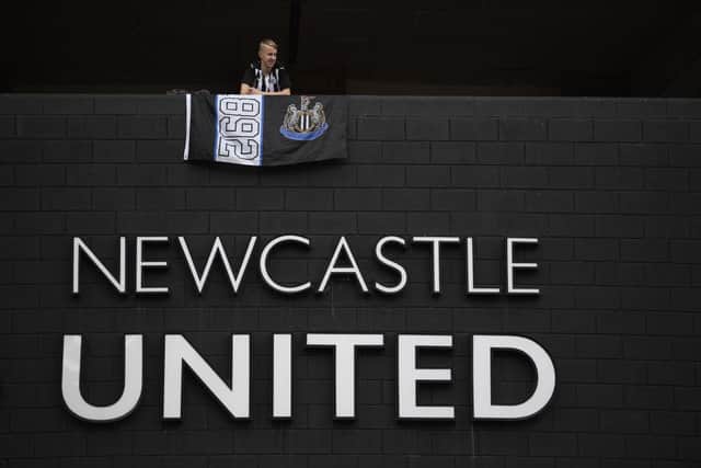 A Newcastle United supporter stands with a flag above the club logo at St James's Park following the takeover.