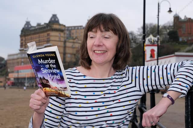 Author Glenda Young on South Bay beach with her first book Murder at the Seaview Hotel which has been nominated for an award