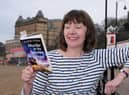 Author Glenda Young on South Bay beach with her first book Murder at the Seaview Hotel which has been nominated for an award