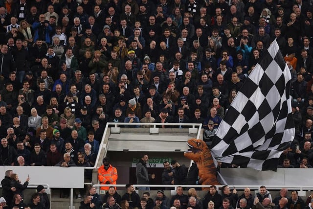 One fan dressed as a T-Rex runs along the Gallowgate with a black-and-white flag during the game with Everton (Photo by George Wood/Getty Images)