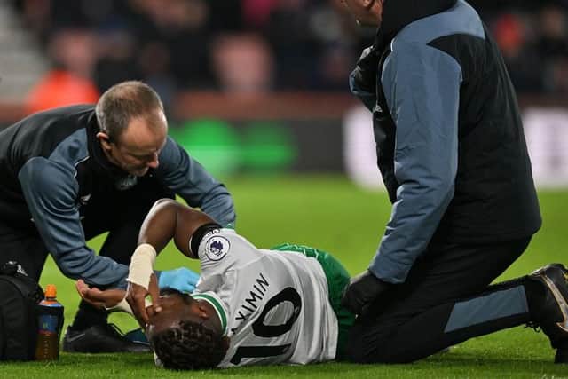 Newcastle United's Allan Saint-Maximin, taken off with an injury, gets medical treatment.