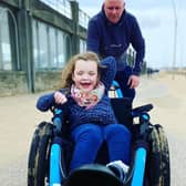 Millie Fountain being pushed in one of the beach wheelchairs by her dad