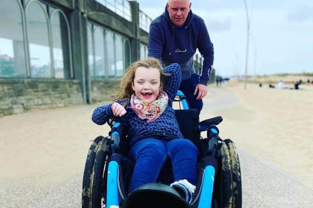 Millie Fountain being pushed in one of the beach wheelchairs by her dad