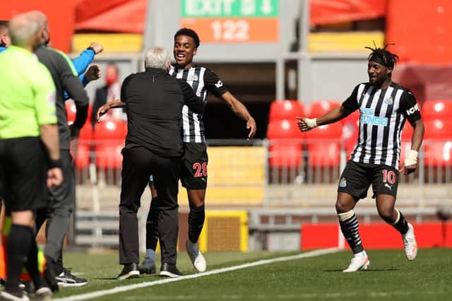 Joe Willock of Newcastle United celebrates with Steve Bruce, Manager of Newcastle United and Allan Saint-Maximin after scoring their side's first goal during the Premier League match between Liverpool and Newcastle United at Anfield on April 24, 2021 in Liverpool, England.