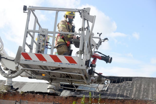 A firefighter tackling the fire from above the roof.