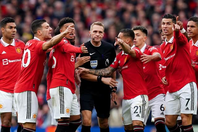 Manchester United players surround referee Craig Pawson at Old Trafford.