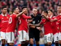 Manchester United players surround referee Craig Pawson at Old Trafford.