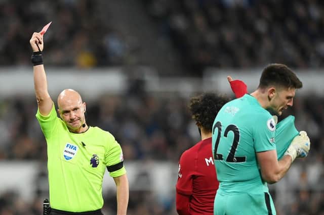 Referee Anthony Taylor shows a red card to Newcastle United's Nick Pope.