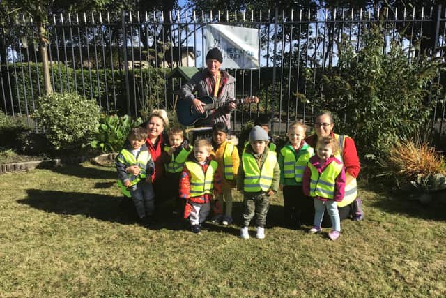 Nurserytime children with 'Tom the music man' at the community garden space in North Marine Park.