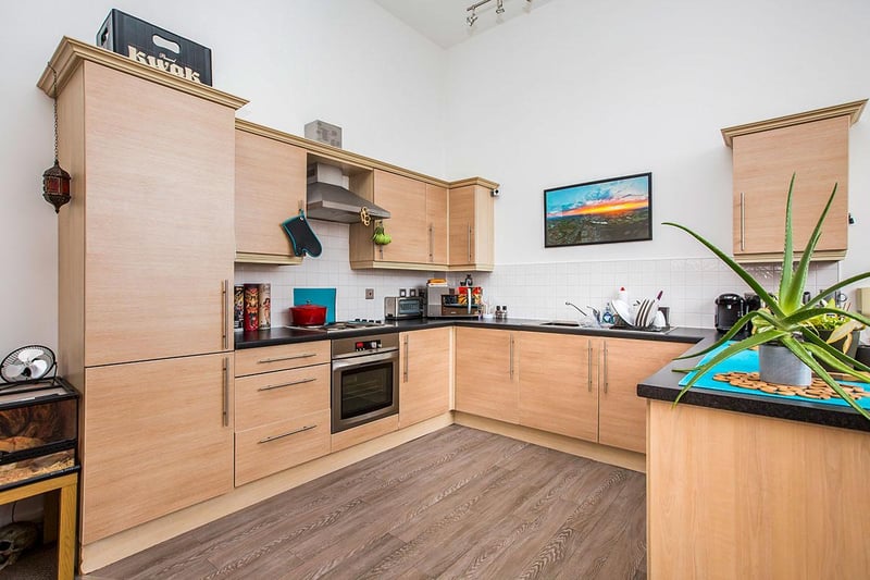 The kitchen is fitted with a modern range of light wood-effect wall-level and base units, as well as drawers.