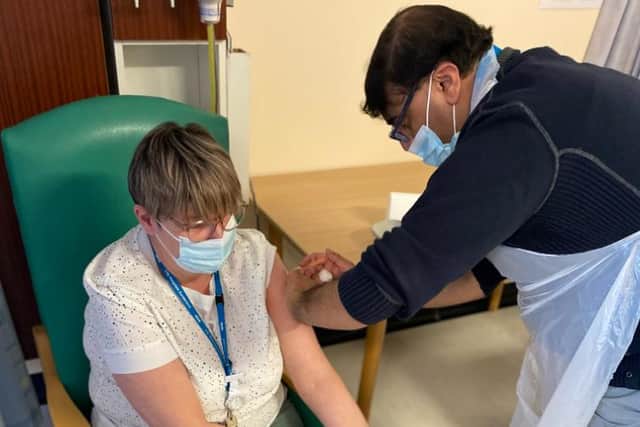 Tracy Barnett, a member of the trust's Community Stroke Team, is given her Covid-19 vaccine by Dr Shaz Wahid, its medical director.