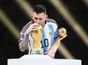Lionel Messi of Argentina kisses the FIFA World Cup Qatar 2022 Winners' Trophy while holding the adidas Golden Boot award after the FIFA World Cup Qatar 2022 Final match between Argentina and France at Lusail Stadium on December 18, 2022 in Lusail City, Qatar. (Photo by Julian Finney/Getty Images)
