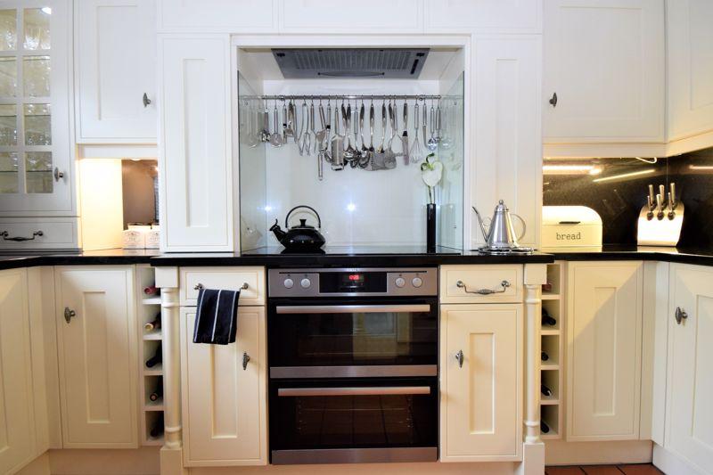 Five-ring induction hob with electric extractor hood over, two electric ovens.