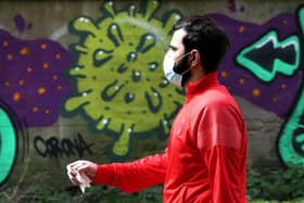 A man wearing a mask walks past coronavirus related graffiti as the UK continues in lockdown to help curb the spread of the coronavirus. Andrew Milligan/PA Wire