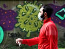 A man wearing a mask walks past coronavirus related graffiti as the UK continues in lockdown to help curb the spread of the coronavirus. Andrew Milligan/PA Wire