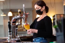 Karine Makarova pulls a pint of Stella Artois behind the bar at the Red Lion & Sun in Highgate, London as outdoor hospitality reopens