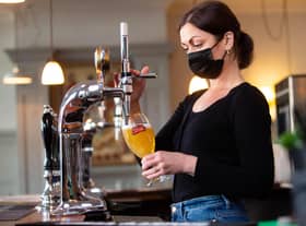 Karine Makarova pulls a pint of Stella Artois behind the bar at the Red Lion & Sun in Highgate, London as outdoor hospitality reopens