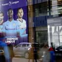 Members of the media are reflected in the glass at the headquarters of the English Premier League in London on March 13, 2020.