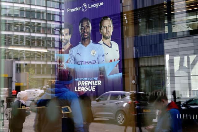 Members of the media are reflected in the glass at the headquarters of the English Premier League in London on March 13, 2020.